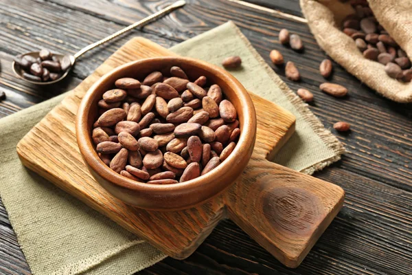 Bowl with aromatic cocoa beans on wooden background — Stock Photo, Image