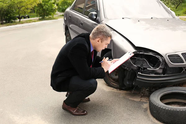 Försäkring man kontrollera trasiga bil — Stockfoto