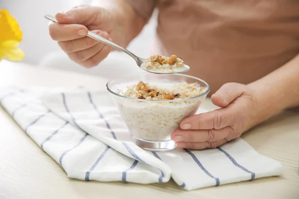 Woman eating oatmeal with milk and walnuts — Stock Photo, Image