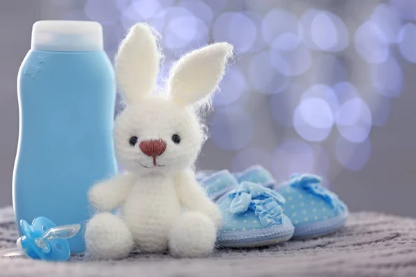 Conejito de juguete de punto, zapatos de bebé y cosméticos — Foto de Stock