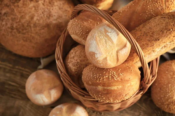 Beautiful composition with wicker basket and delicious bread on wooden table — Stock Photo, Image