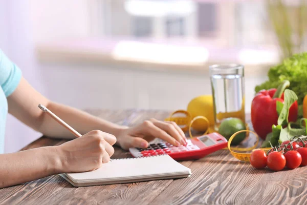 Mujer joven calculando calorías en la mesa. Concepto de pérdida de peso —  Fotos de Stock