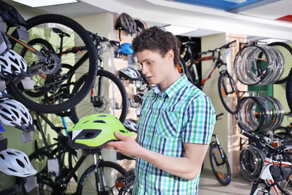 Jongeman fiets helm in winkel kiezen — Stockfoto