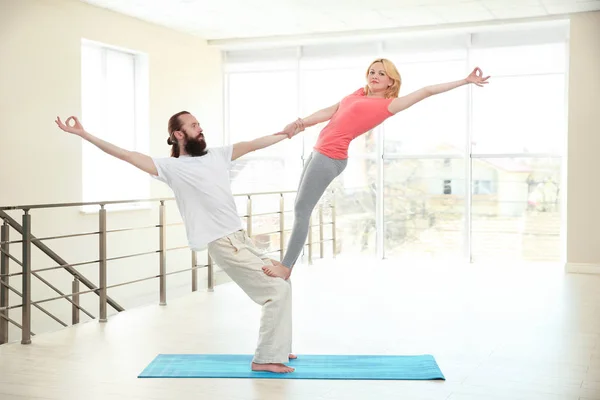 Jong koppel beoefenen van yoga op lichte kamer — Stockfoto