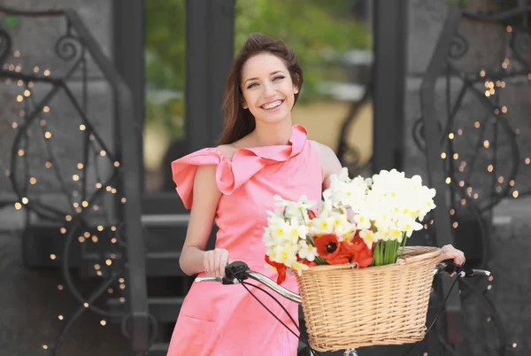 Jong meisje met fiets- en mand van bloemen — Stockfoto