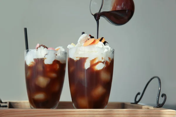 Belag auf Dessert mit kaltem Brühkaffee im Glas auf Holztablett gießen — Stockfoto