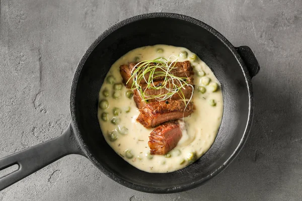 Frigideira com bife fatiado e molho em fundo cinza — Fotografia de Stock