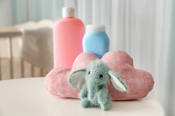 Cute knitted toy elephant and cosmetics for baby on table — Stock Photo, Image