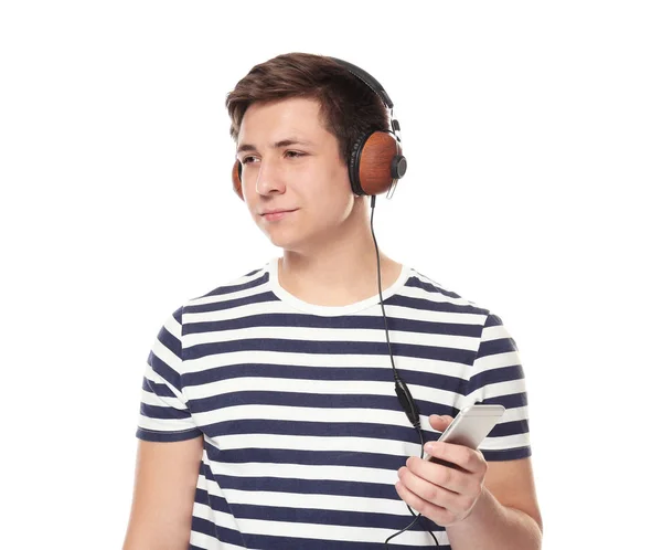 Lindo adolescente con teléfono móvil y auriculares escuchando música sobre fondo blanco —  Fotos de Stock