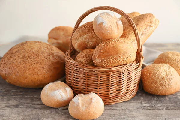 Bela composição com cesta de vime e delicioso pão na mesa de madeira — Fotografia de Stock