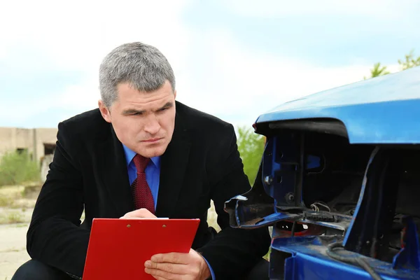 Hombre de seguros comprobando coche roto — Foto de Stock