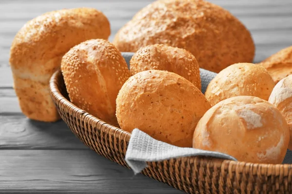 Cesta de vime e pão delicioso na mesa de madeira — Fotografia de Stock