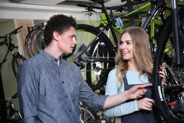 Jonge man en mooie vrouw controleren fiets in reparatie winkel — Stockfoto