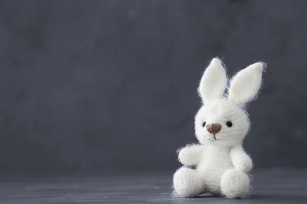 Bonito coelho de brinquedo de malha no fundo cinza — Fotografia de Stock