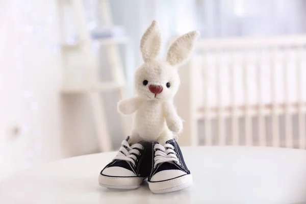 Cute knitted toy bunny and baby shoes — Stock Photo, Image