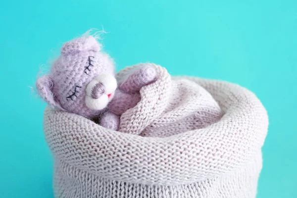 Leuke handgemaakte toy bear slapen in gebreide tas op kleur achtergrond — Stockfoto