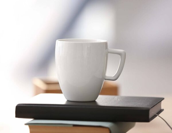 Белая чашка на книги в офисе

