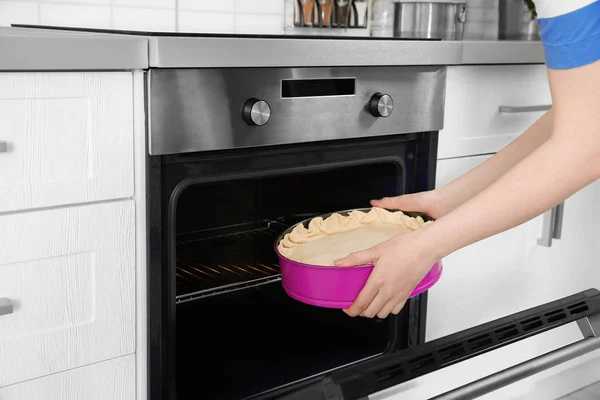 Young woman putting baking dish with pie into oven. Concept of cooking classes — Stock Photo, Image