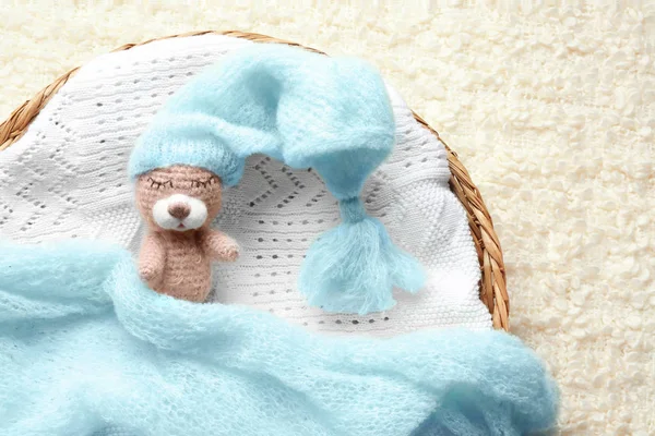 Cesto di vimini con simpatico orso giocattolo addormentato su plaid leggero — Foto Stock