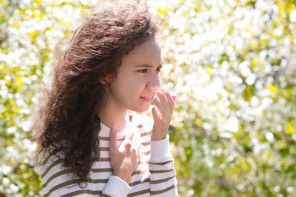 Anti kavramı. Genç kadın öksürük Park çiçek açan ağaçlar arasında acı
