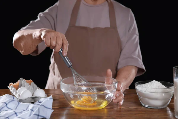 Пожилая женщина делает тесто в миске на столе — стоковое фото