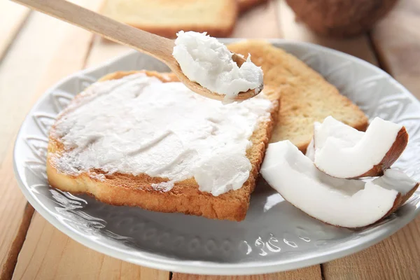 Delicious toasts with coconut oil in plate on table — Stock Photo, Image