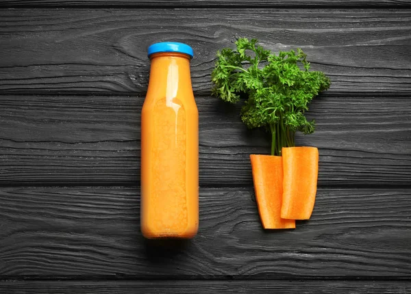 Bottiglia di frullato fresco, fette di carota e prezzemolo su fondo di legno — Foto Stock