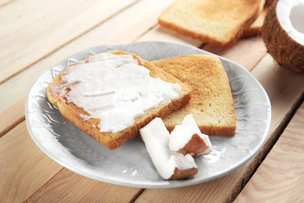 Delicious toasts with coconut oil in plate — Stock Photo, Image