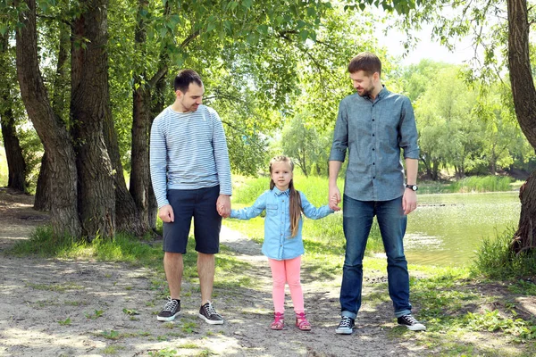 Smiling gay couple with daughter in park — Stock Photo, Image