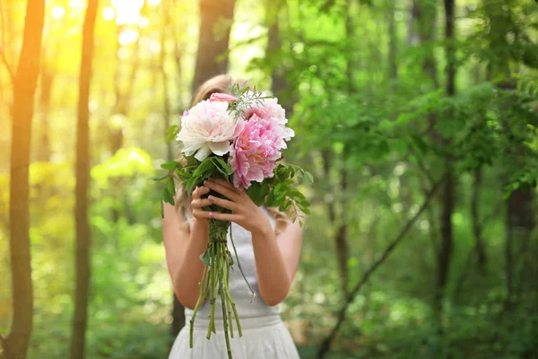 Mulher bonita com buquê de peônias na floresta — Fotografia de Stock