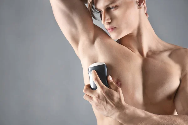 Yakışıklı delikanlı ile deodorant gri arka plan üzerinde — Stok fotoğraf