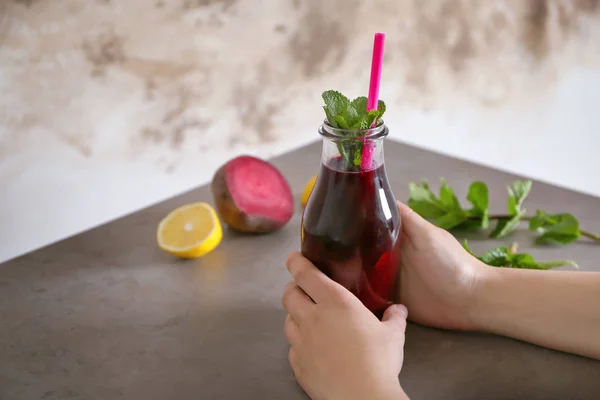 Mujer joven sosteniendo vaso de batido de remolacha — Foto de Stock