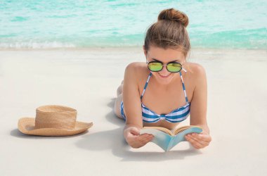 Güzel genç kadın deniz sahilde yalan kitap okuma