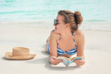 Güzel genç kadın deniz sahilde yalan kitap okuma