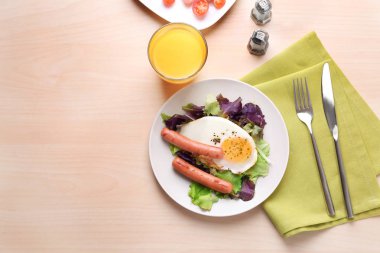 Ev yapımı kızarmış yumurta, sosis ve masada karışımı salata ile plaka