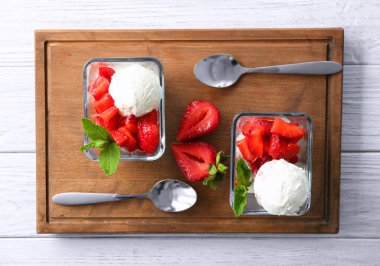 Kase lezzetli dilimlenmiş çilek ve ahşap masa üzerinde dondurma ile