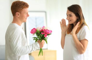 Genç adam sevgilisini ışık Oda güzel çiçekler buket sunmak