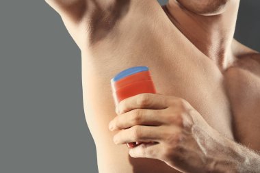 Yakışıklı delikanlı ile deodorant gri arka plan üzerinde