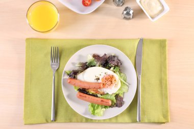 Ev yapımı kızarmış yumurta, sosis ve masada karışımı salata ile plaka