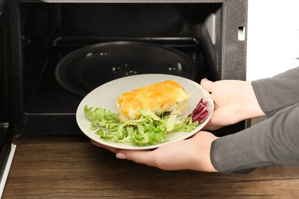 Plaka lezzetli güveç ve karışık salata ile mikrodalga koyarak kadın