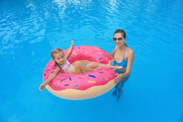 Jovem e sua filha com donut inflável na piscina — Fotografia de Stock