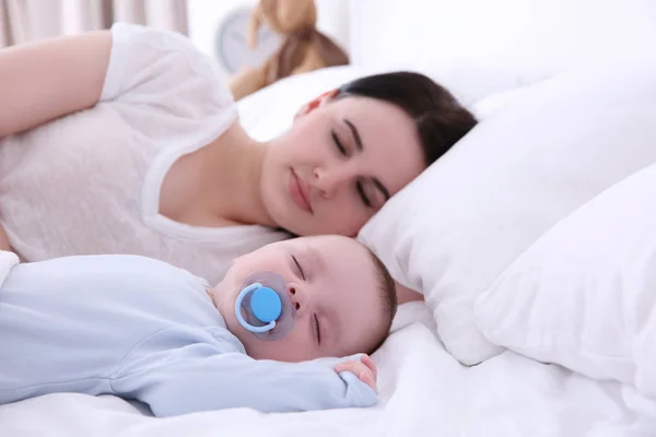 Wanita muda dengan bayi lucu tidur di tempat tidur — Stok Foto