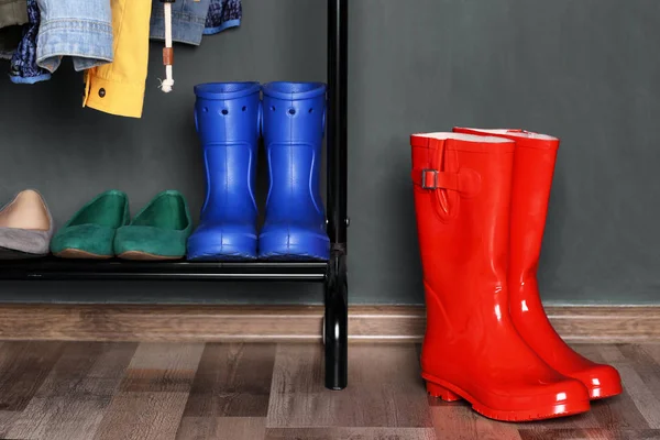 Shelf with different shoes and red wellington boots — Stock Photo, Image