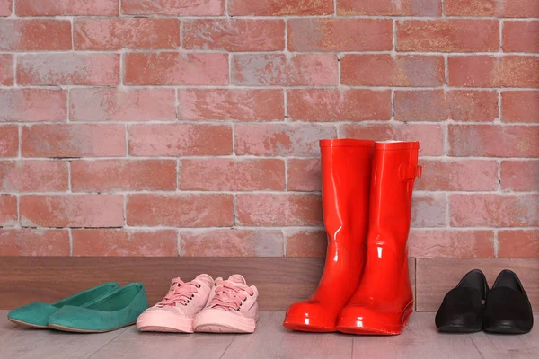 Red wellington boots and different shoes — Stock Photo, Image
