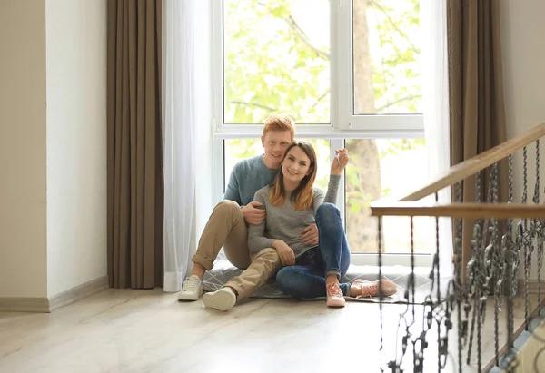 可爱的夫妇坐在靠近窗口的钥匙从新的公寓 — 图库照片