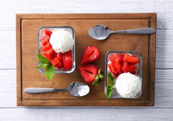 Kase lezzetli dilimlenmiş çilek ve ahşap masa üzerinde dondurma ile