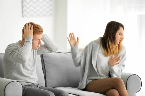 Pasangan muda berdebat sambil duduk di sofa di ruang cahaya — Stok Foto