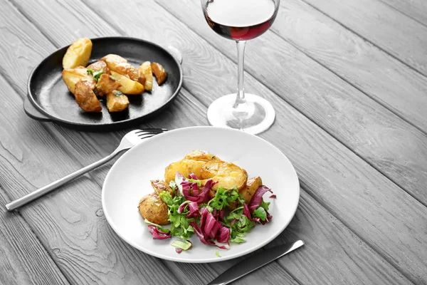 Smaczny obiad z ziemniaków, Sałatka oraz kieliszek wina na stole — Zdjęcie stockowe