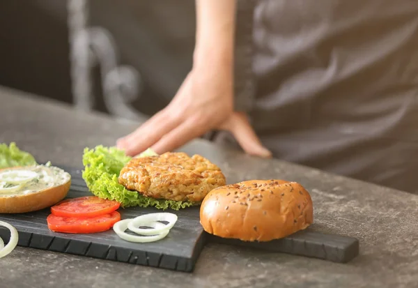 Woman cooking tasty turkey burger — Stock Photo, Image