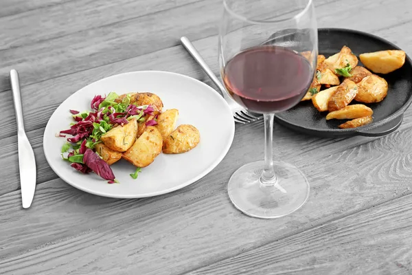 Tasty dinner with potato, mixed salad and glass of wine on table